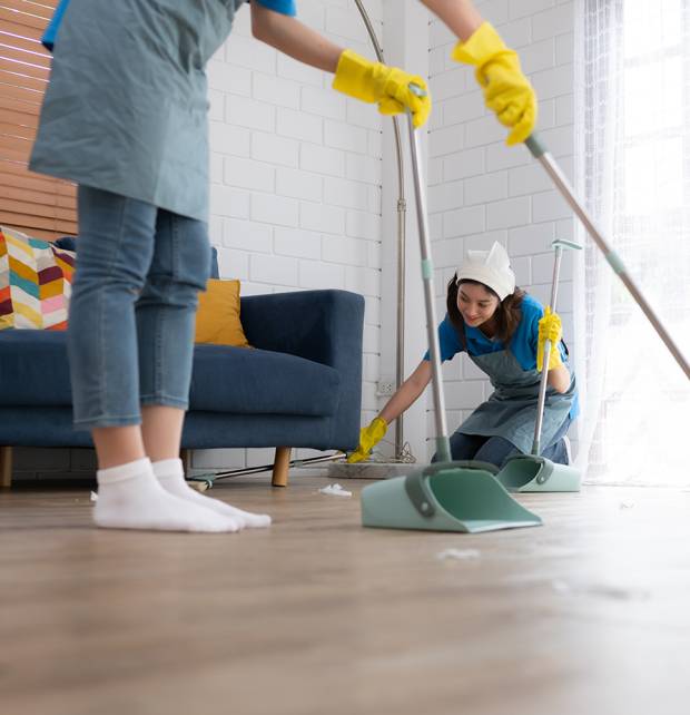 Cleaning service. Dark-haired woman wearing a white hat and yellow gloves cleaning the floor